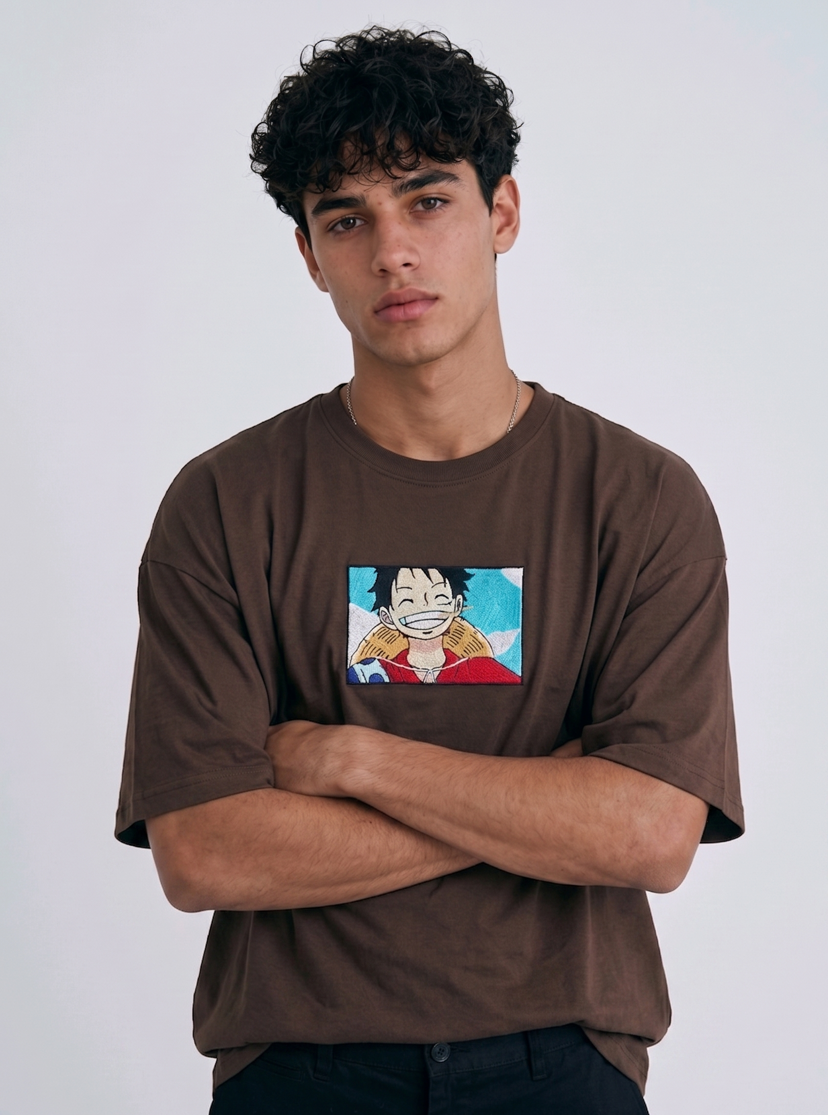
A full-body studio photograph of a male model wearing an Anetoonz black oversized crewneck t-shirt featuring a framed graphic print of a smiling Monkey D. Luffy with a straw hat against a colorful background.