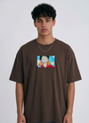 A full-body studio photograph of a male model wearing an Anetoonz black oversized crewneck t-shirt featuring a framed graphic print of a smiling Monkey D. Luffy with a straw hat against a colorful background.