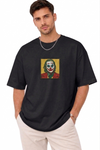"A man wearing an Anetoonz oversized black half-sleeve T-shirt featuring a square direct embroidery of the Joker character on the chest."