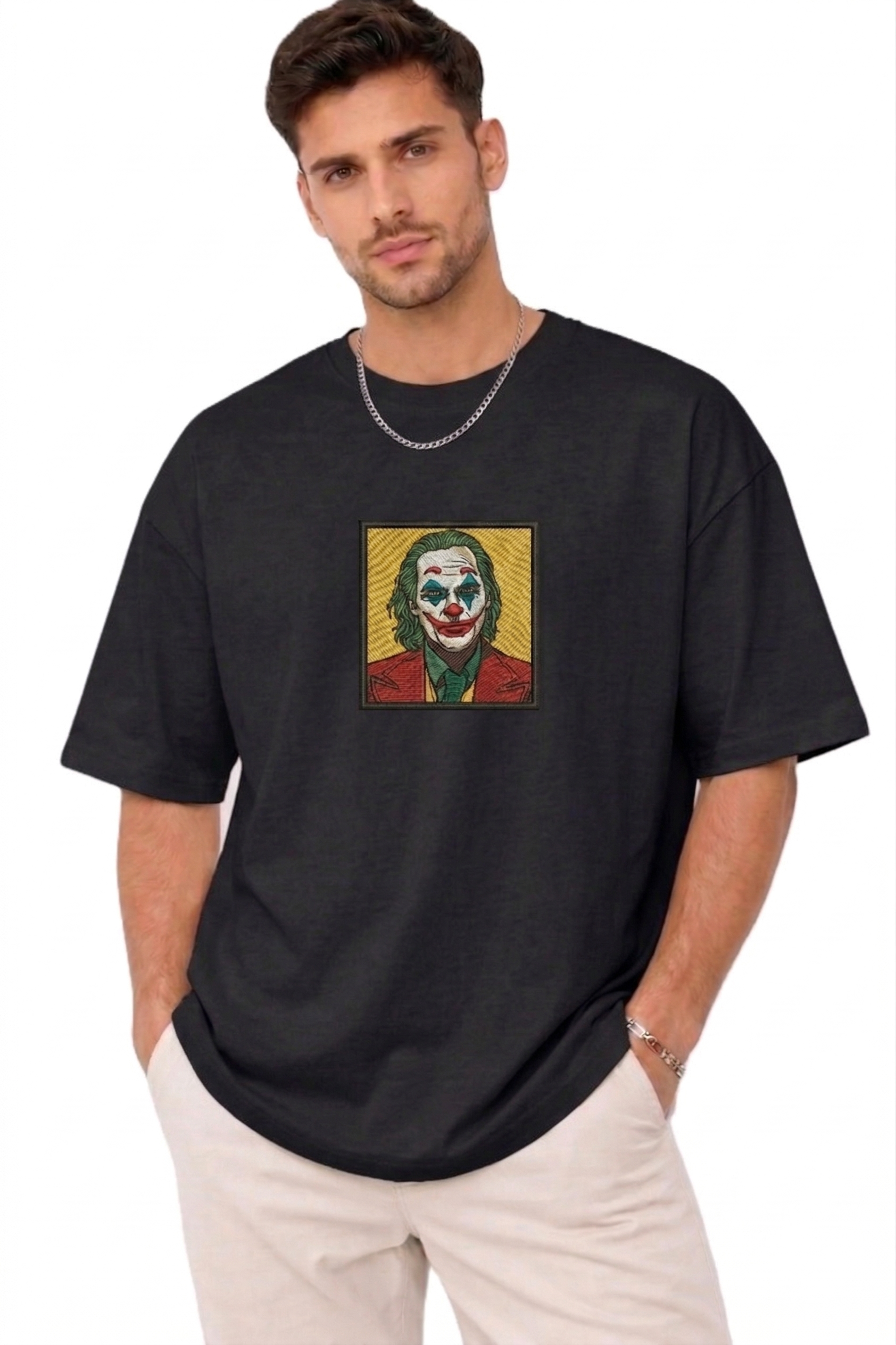 "A man wearing an Anetoonz oversized black half-sleeve T-shirt featuring a square direct embroidery of the Joker character on the chest."