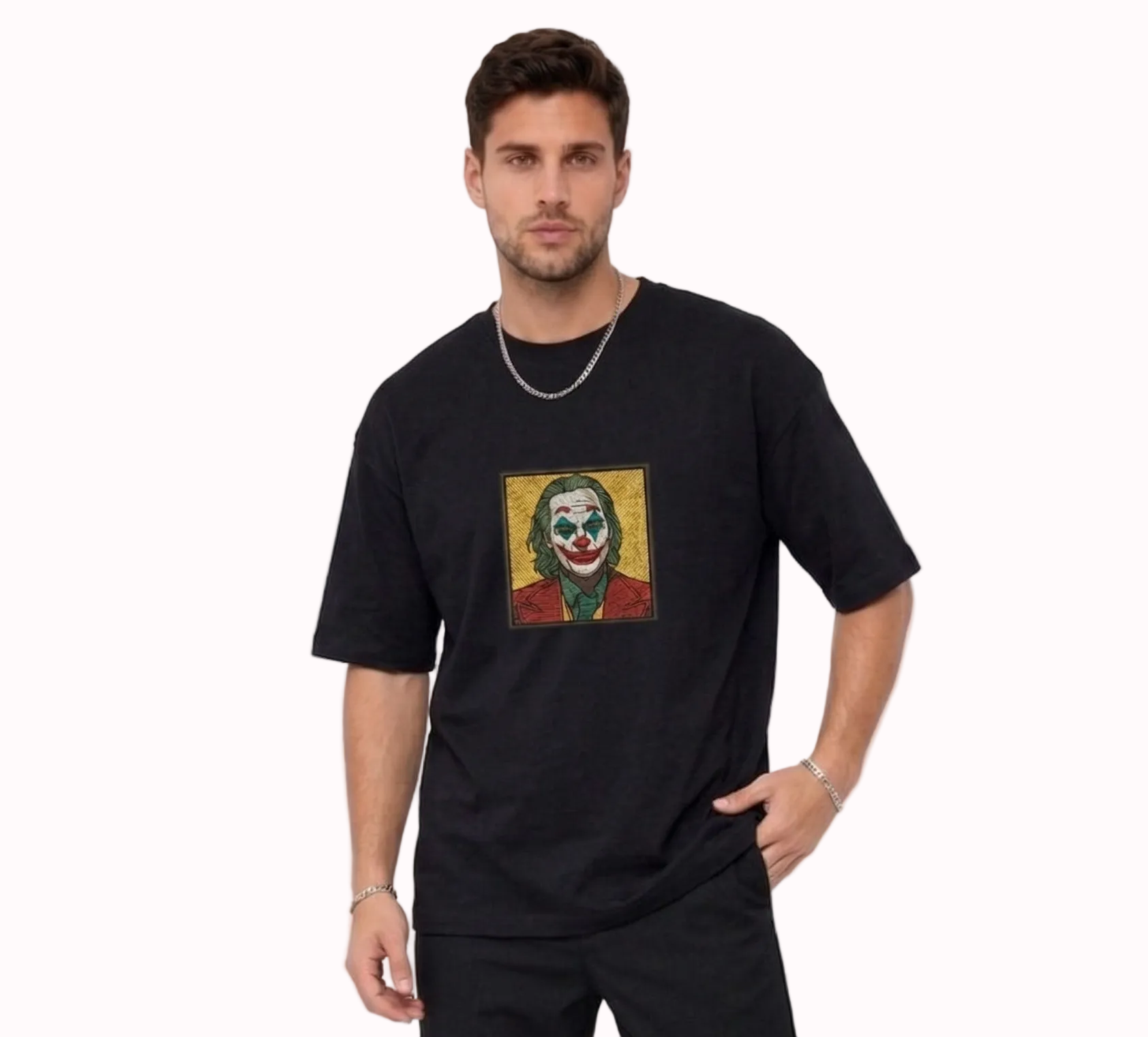 "A man wearing an Anetoonz oversized black half-sleeve T-shirt featuring a square direct embroidery of the Joker character on the chest."