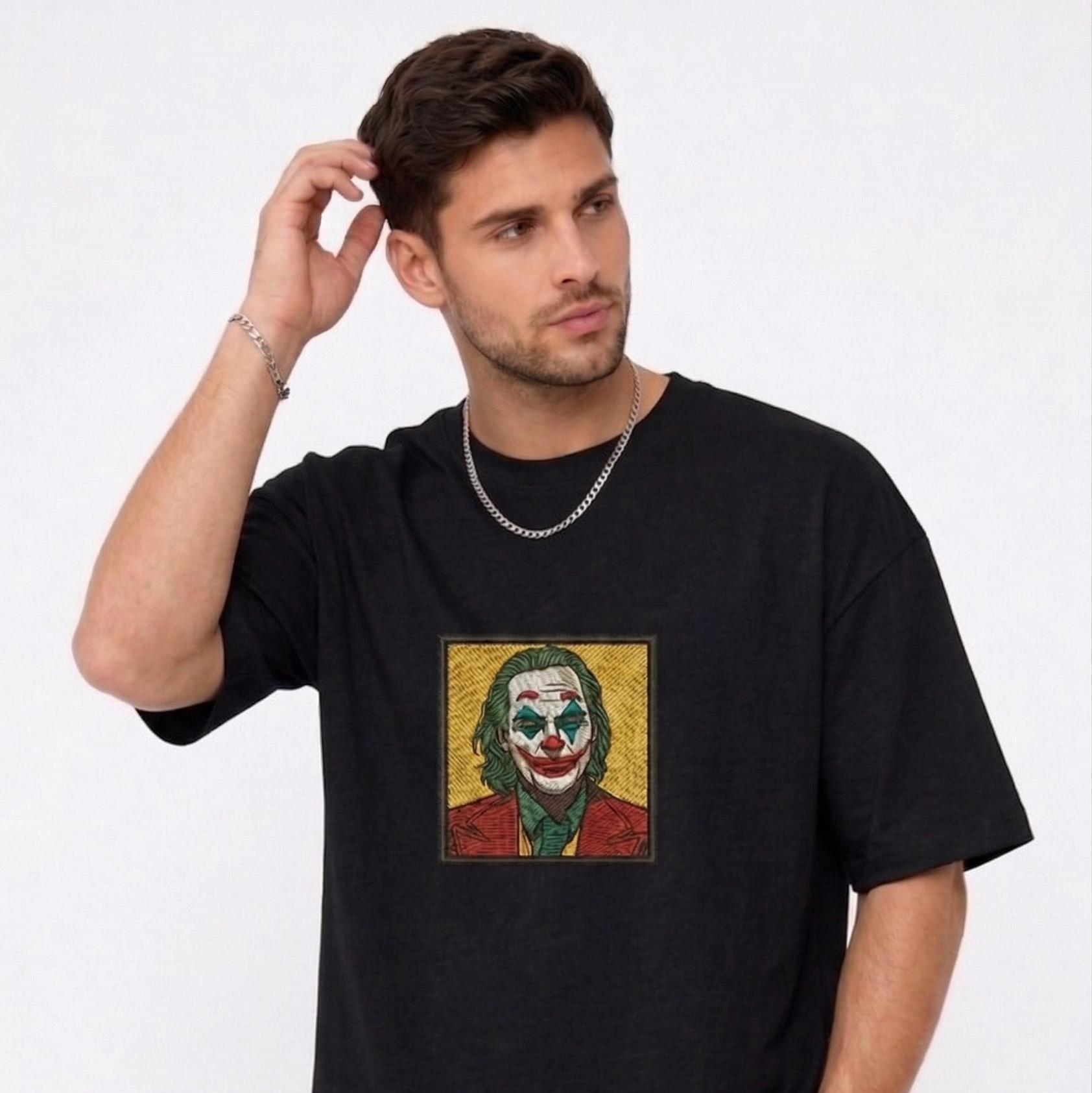 "A man wearing an Anetoonz oversized black half-sleeve T-shirt featuring a square direct embroidery of the Joker character on the chest."