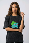 A female model wearing an Acid-Wash oversized t-shirt featuring a detailed green and blue Bulbasaur character embroidered in the center of the chest.