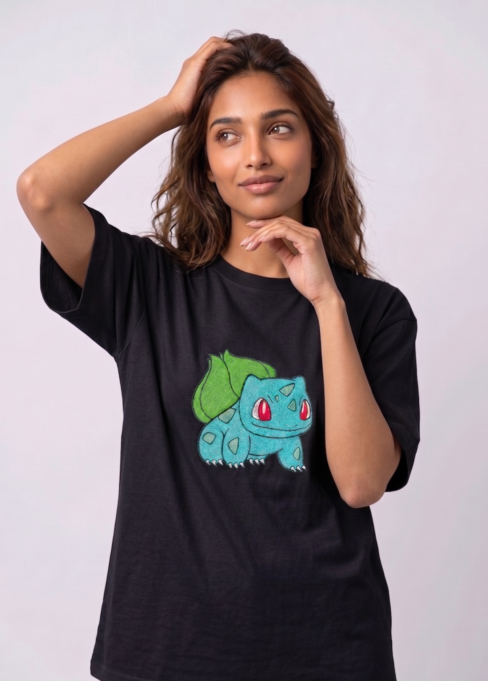 A female model wearing an Black oversized t-shirt featuring a detailed green and blue Bulbasaur character embroidered in the center of the chest.