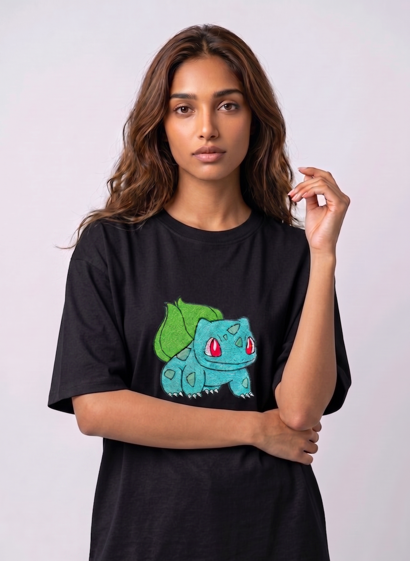 A female model wearing an Black oversized t-shirt featuring a detailed green and blue Bulbasaur character embroidered in the center of the chest.