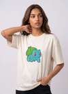 A female model wearing an off-white oversized t-shirt featuring a detailed green and blue Bulbasaur character embroidered in the center of the chest.