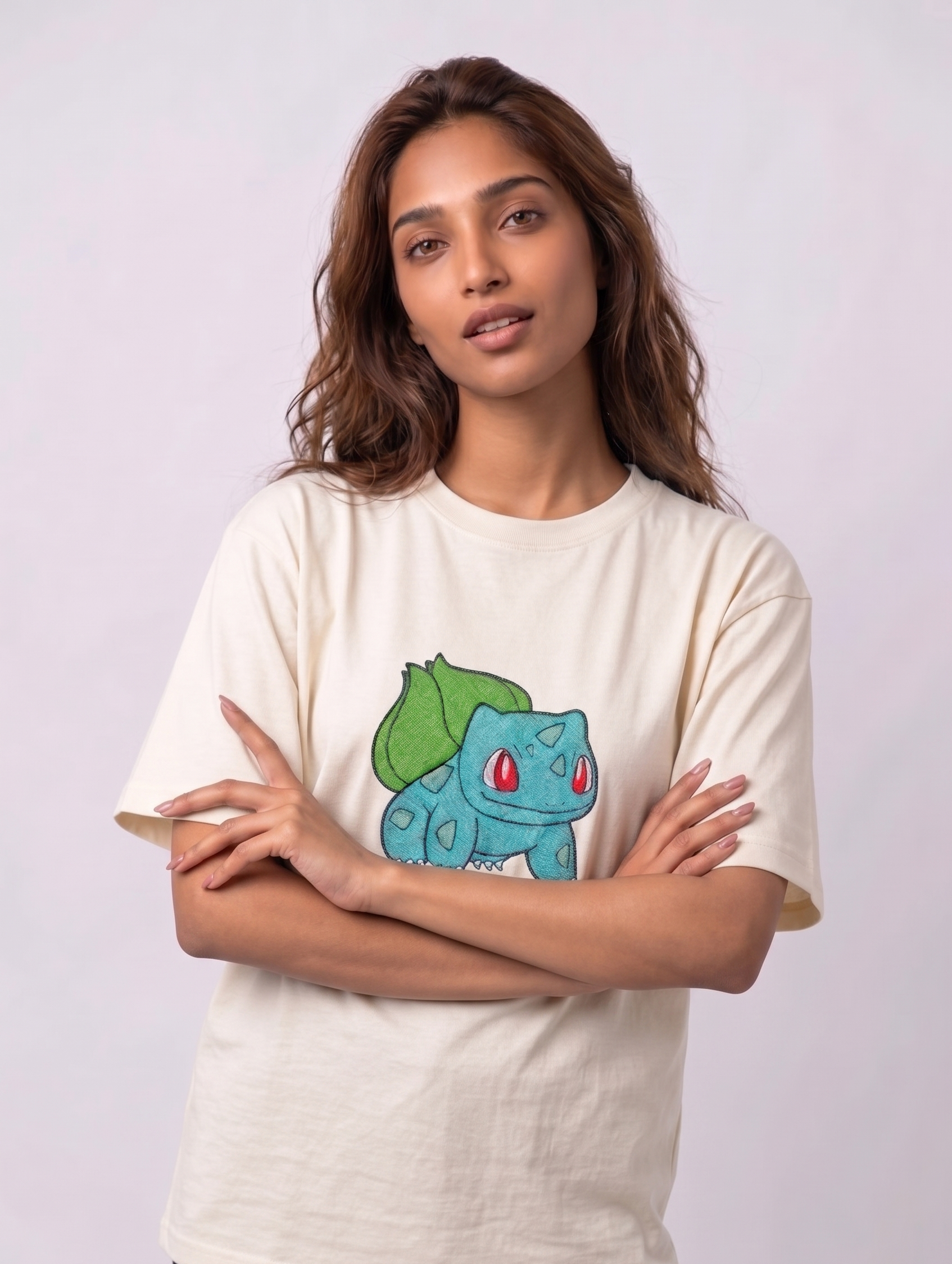 A female model wearing an off-white oversized t-shirt featuring a detailed green and blue Bulbasaur character embroidered in the center of the chest.