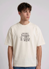 Wearing a cream-colored, crew-neck t-shirt. The center of the chest features a minimalist black line-art embroidery depicting a classic cafe storefront.
