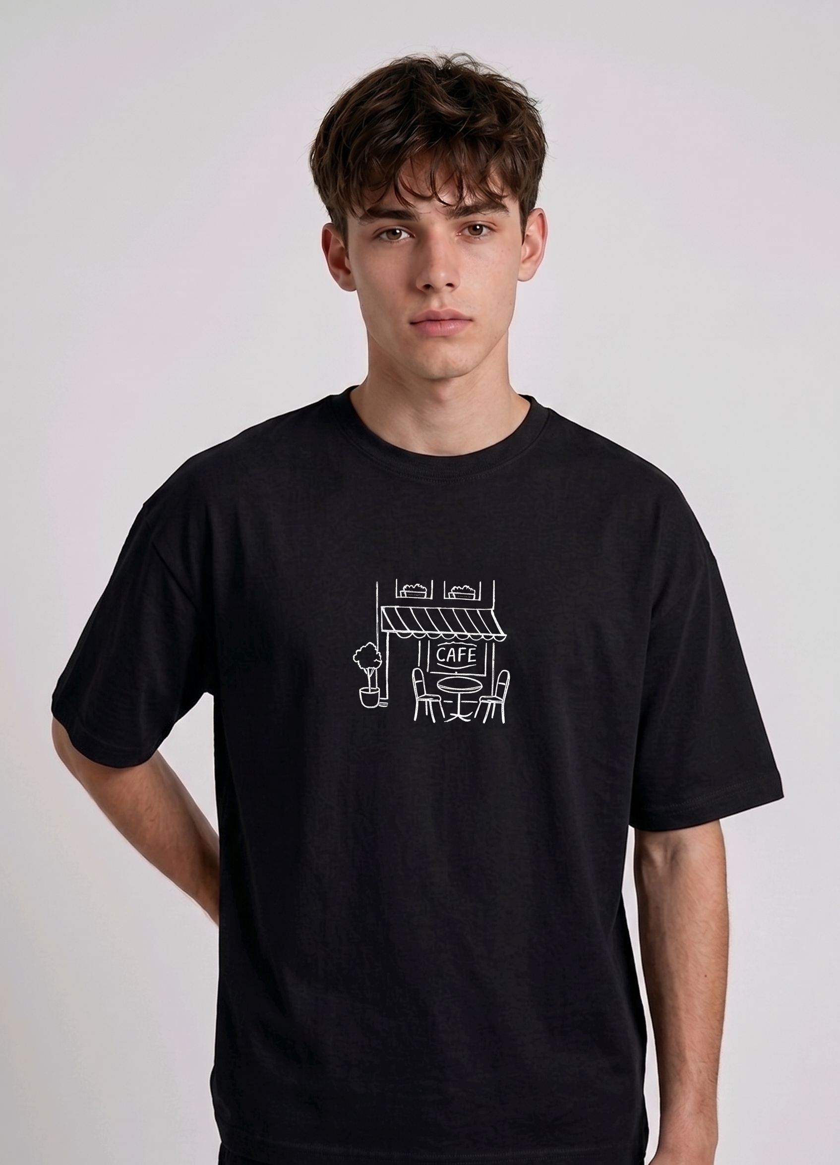 Wearing Black-colored, crew-neck t-shirt. The center of the chest features a minimalist white line-art embroidery depicting a classic cafe storefront.
