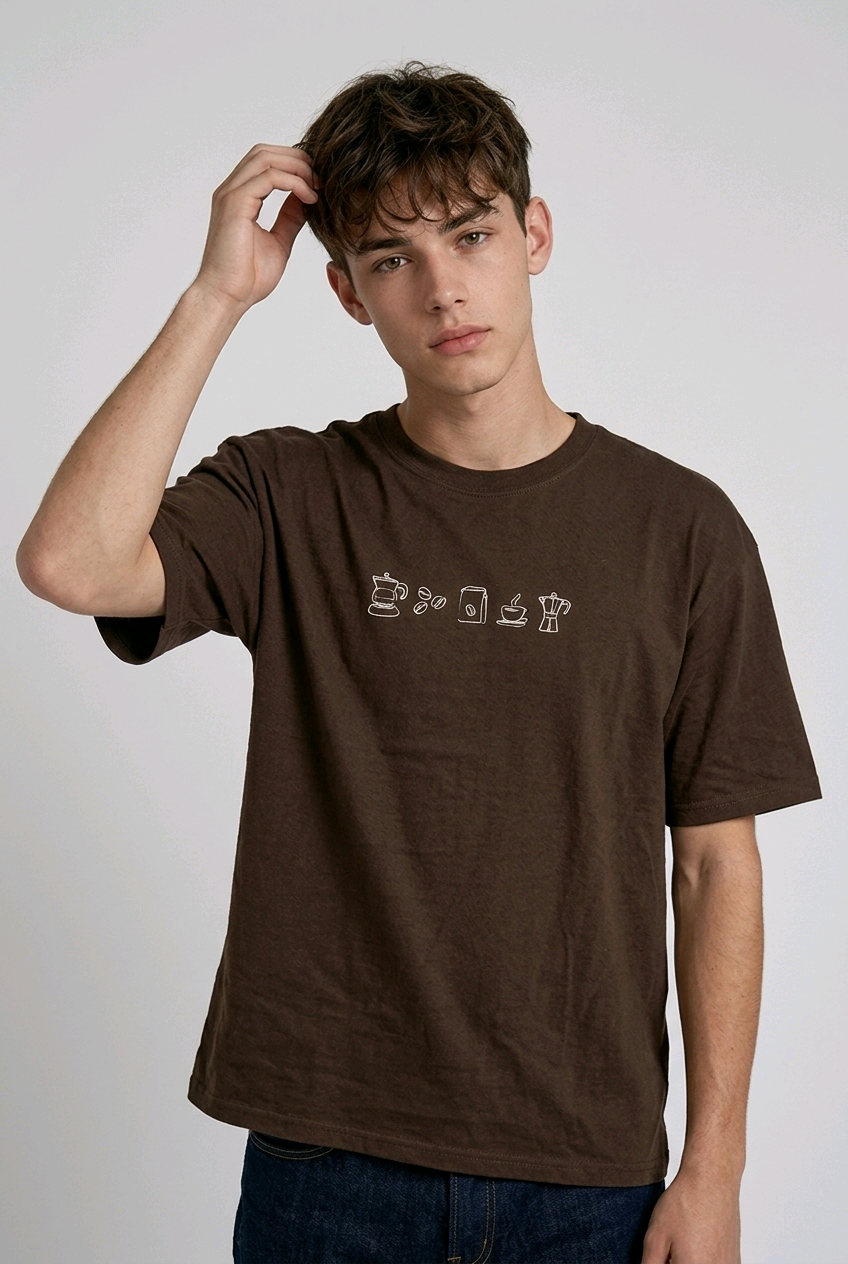 wearing an oversized, half-sleeved heavyweight cotton t-shirt. The chest features high-density direct embroidery of five minimalist coffee-themed icons in a horizontal row, including a French press, coffee beans, a coffee bag, a steaming cup, and a moka pot.
