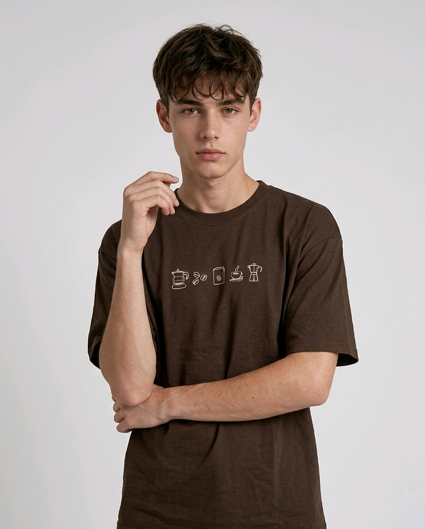 wearing an oversized, half-sleeved heavyweight cotton t-shirt. The chest features high-density direct embroidery of five minimalist coffee-themed icons in a horizontal row, including a French press, coffee beans, a coffee bag, a steaming cup, and a moka pot.
