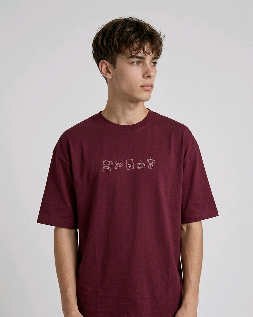 wearing an oversized, half-sleeved heavyweight cotton t-shirt. The chest features high-density direct embroidery of five minimalist coffee-themed icons in a horizontal row, including a French press, coffee beans, a coffee bag, a steaming cup, and a moka pot.
