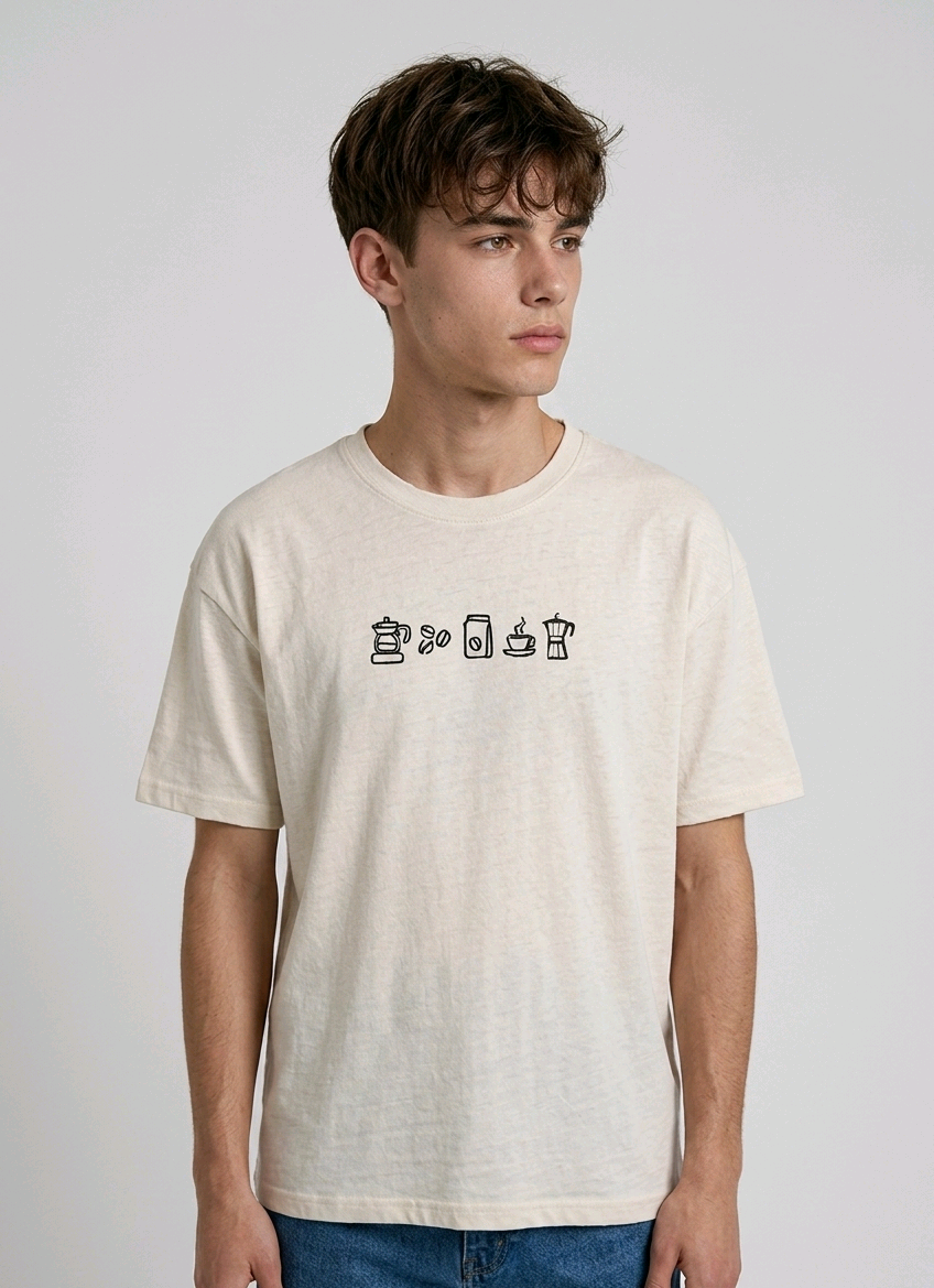 wearing an oversized, half-sleeved heavyweight cotton t-shirt. The chest features high-density direct embroidery of five minimalist coffee-themed icons in a horizontal row, including a French press, coffee beans, a coffee bag, a steaming cup, and a moka pot.
