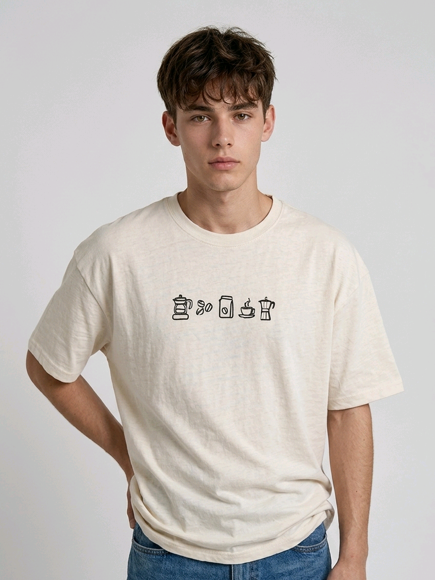wearing an oversized, half-sleeved heavyweight cotton t-shirt. The chest features high-density direct embroidery of five minimalist coffee-themed icons in a horizontal row, including a French press, coffee beans, a coffee bag, a steaming cup, and a moka pot.

