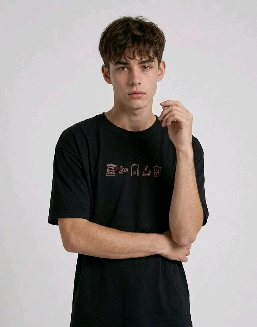 wearing an oversized, half-sleeved heavyweight cotton t-shirt. The chest features high-density direct embroidery of five minimalist coffee-themed icons in a horizontal row, including a French press, coffee beans, a coffee bag, a steaming cup, and a moka pot.
