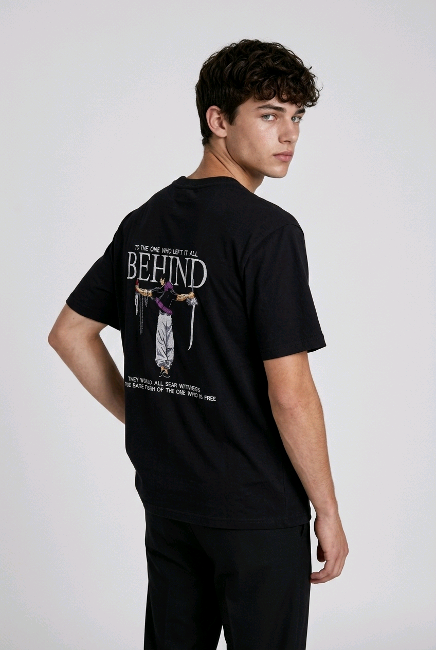 A male model from the back, wearing a black oversized t-shirt with a large, detailed embroidery design.
