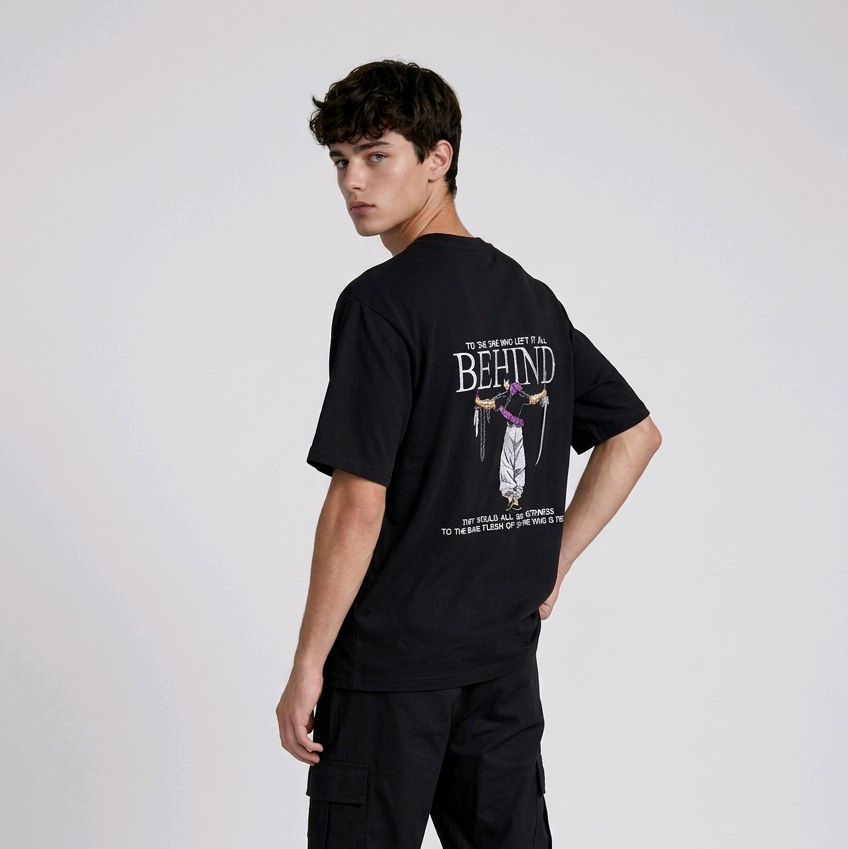 A male model from the back, wearing a black oversized t-shirt with a large, detailed embroidery design.
