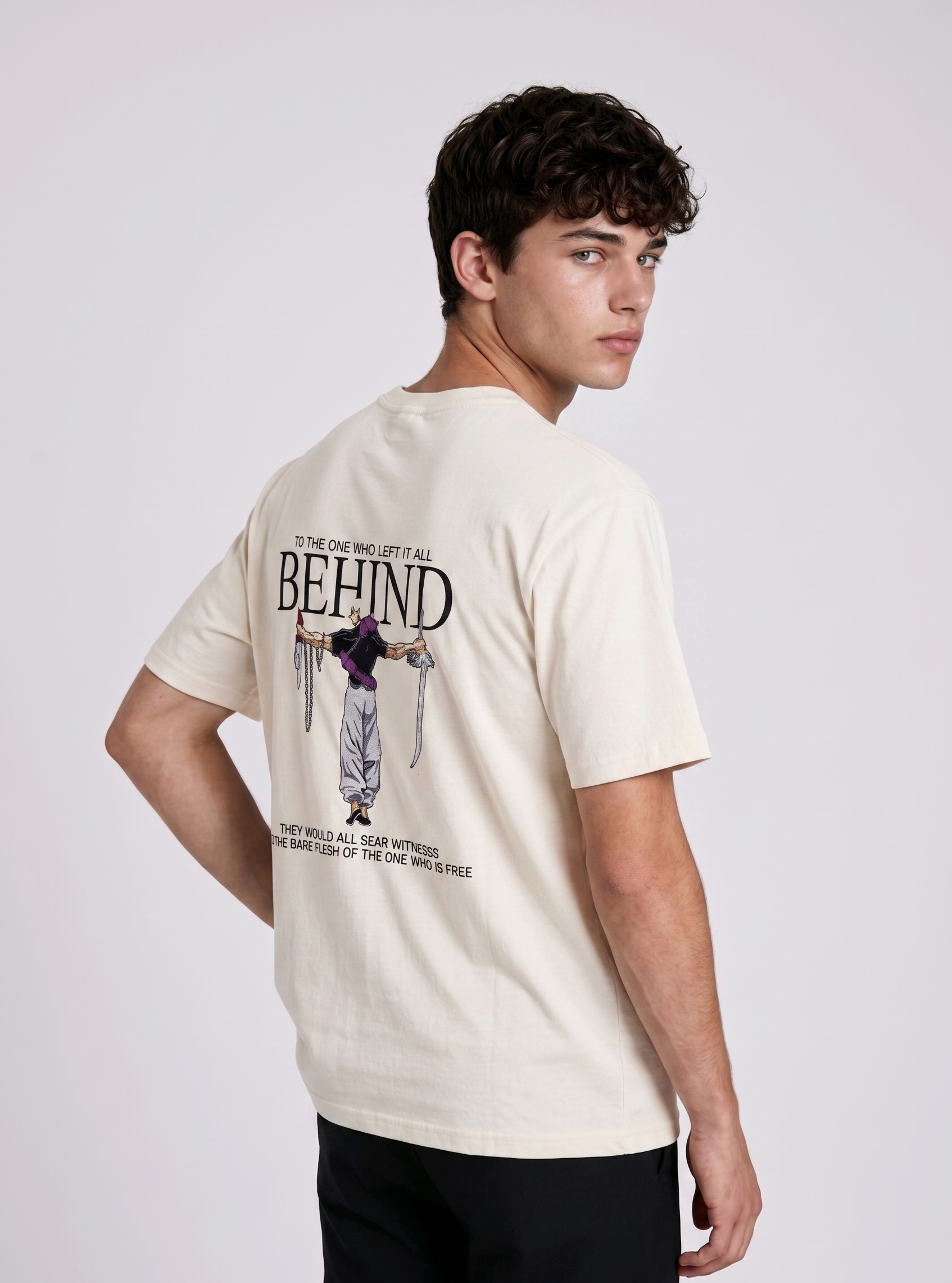 A male model from the back, wearing a black oversized t-shirt with a large, detailed embroidery design.
