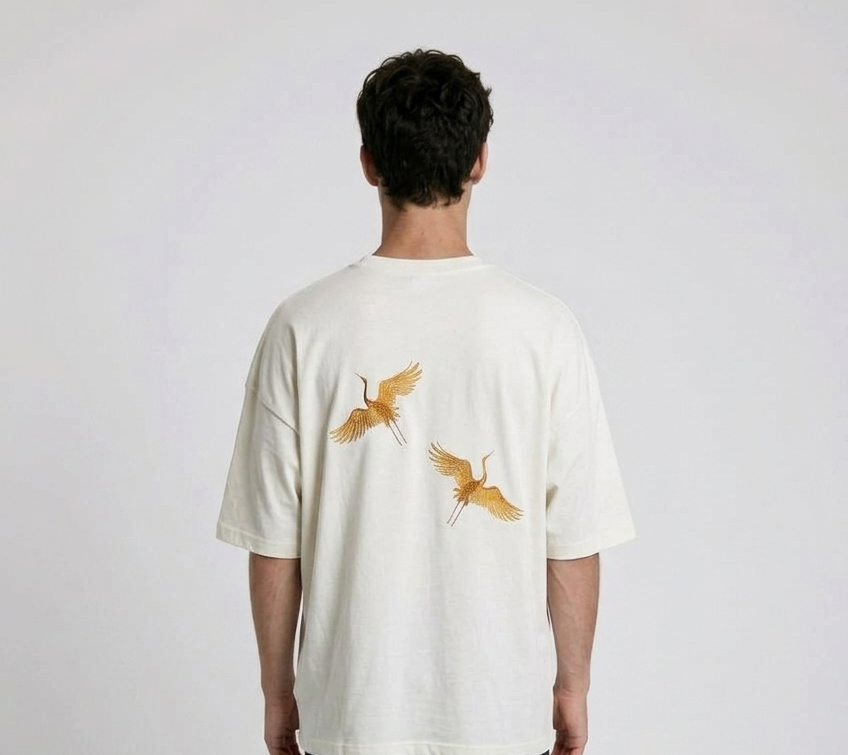 Rear view of a person wearing a heavyweight oversized half-sleeved t-shirt featuring high-density direct embroidery of two golden cranes on the back.

