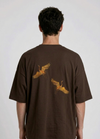 Rear view of a person wearing a heavyweight oversized half-sleeved t-shirt featuring high-density direct embroidery of two golden cranes on the back.

