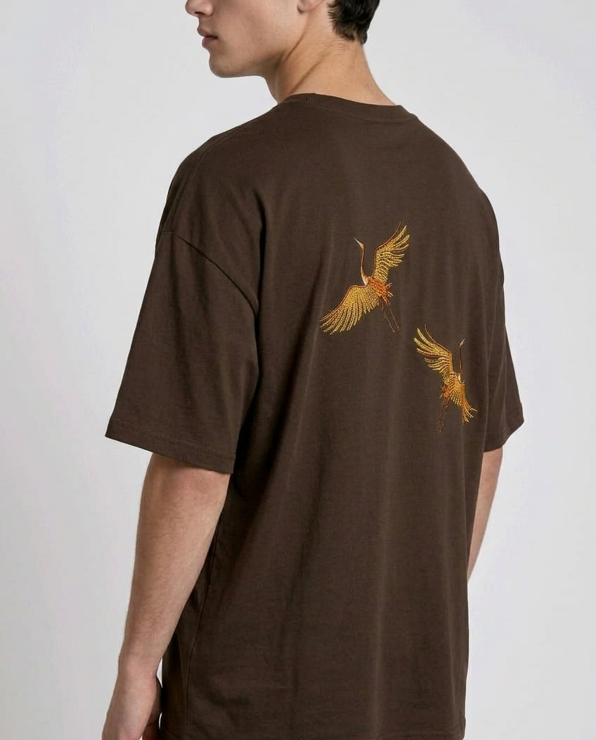 Rear view of a person wearing a heavyweight oversized half-sleeved t-shirt featuring high-density direct embroidery of two golden cranes on the back.