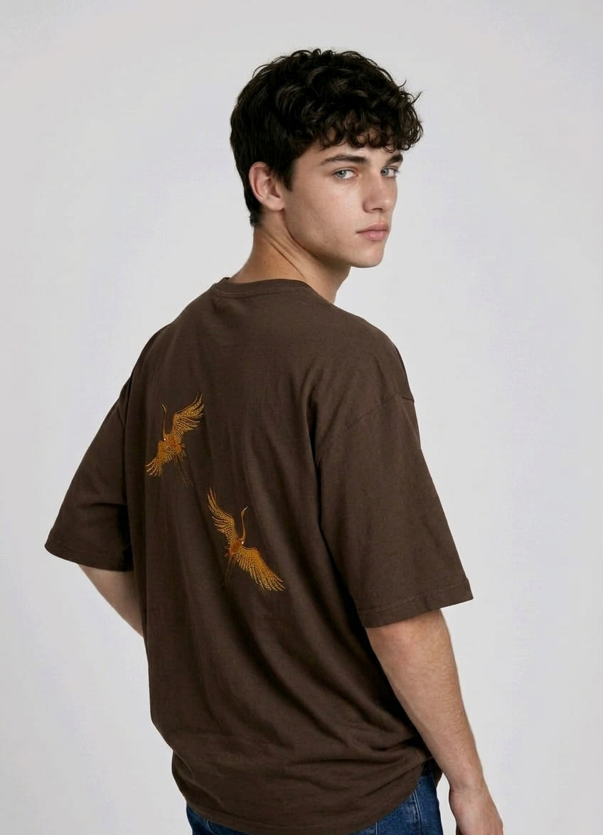 Rear view of a person wearing a heavyweight oversized half-sleeved t-shirt featuring high-density direct embroidery of two golden cranes on the back.