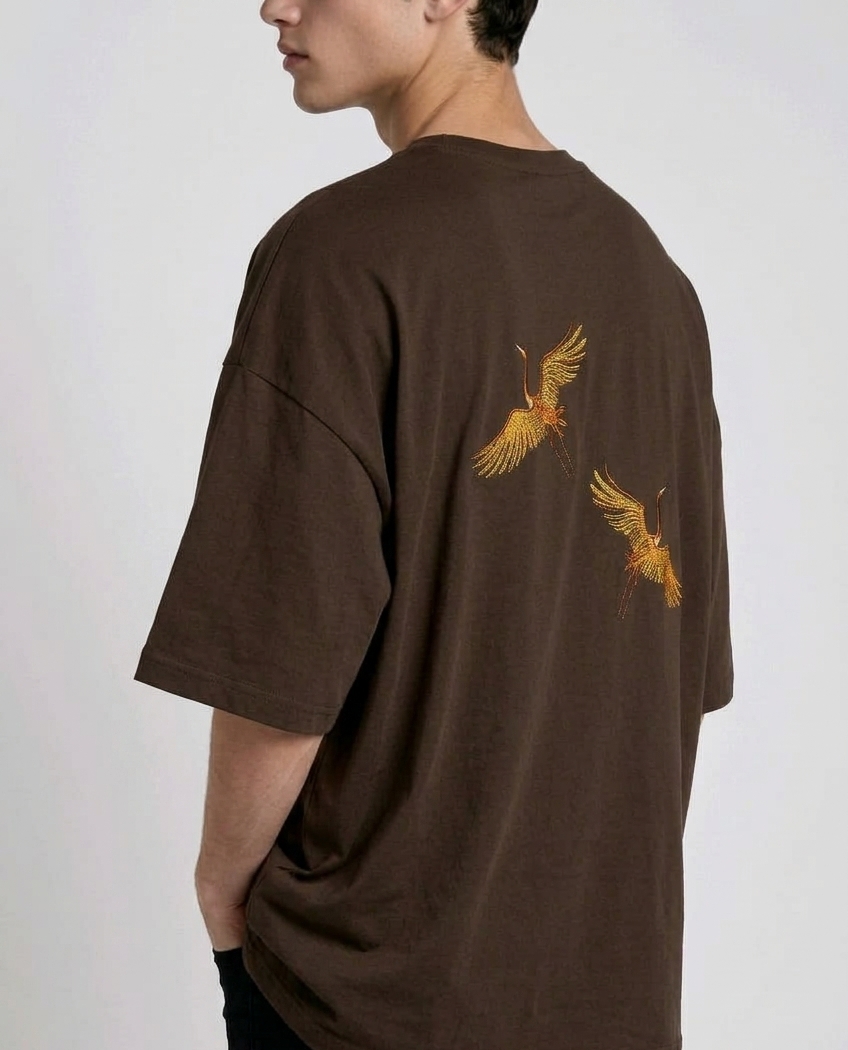 Rear view of a person wearing a heavyweight oversized half-sleeved t-shirt featuring high-density direct embroidery of two golden cranes on the back.