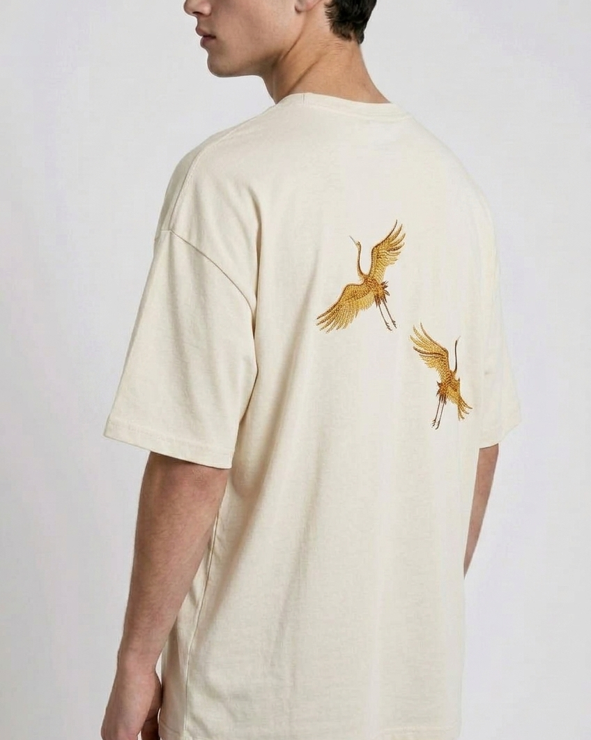 Rear view of a person wearing a heavyweight oversized half-sleeved t-shirt featuring high-density direct embroidery of two golden cranes on the back.

