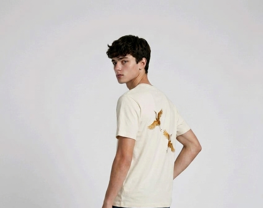 Rear view of a person wearing a heavyweight oversized half-sleeved t-shirt featuring high-density direct embroidery of two golden cranes on the back.

