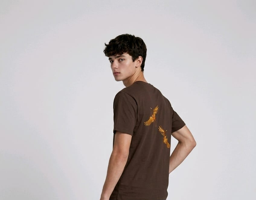 Rear view of a person wearing a heavyweight oversized half-sleeved t-shirt featuring high-density direct embroidery of two golden cranes on the back.

