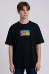 He is wearing a dark, heavyweight cotton t-shirt with a detailed, colorful embroidered patch on the chest featuring anime characters Ash Ketchum (winking) and Pikachu.