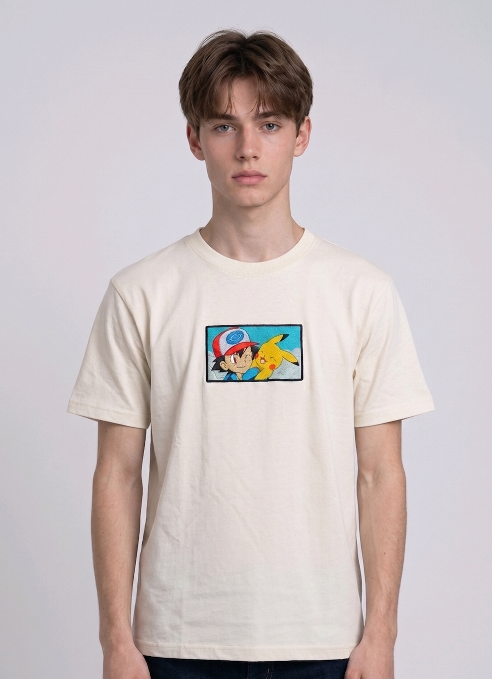 He is wearing  heavyweight cotton t-shirt with a detailed, colorful embroidered patch on the chest featuring anime characters Ash Ketchum (winking) and Pikachu.