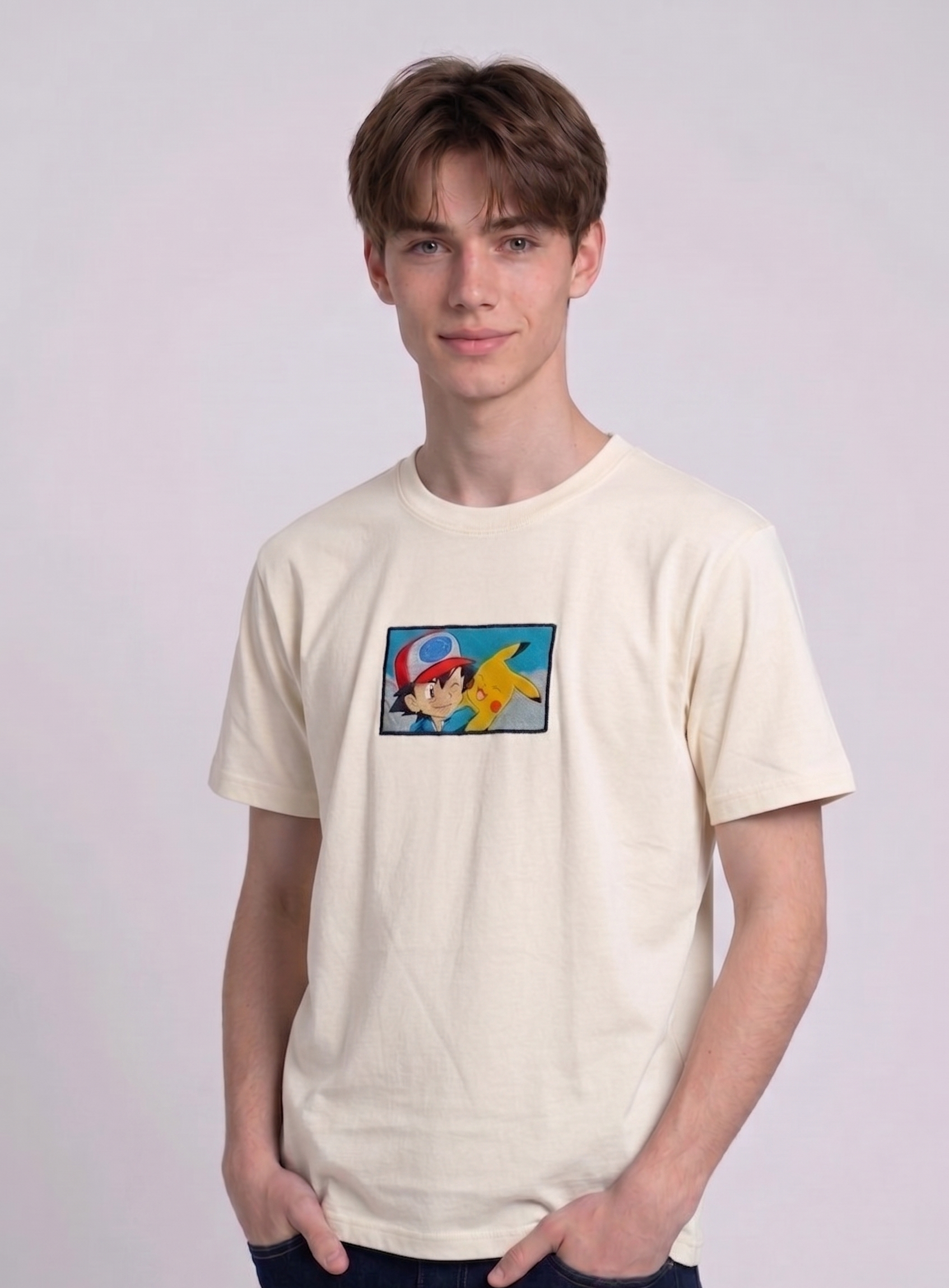 He is wearing , heavyweight cotton t-shirt with a detailed, colorful embroidered patch on the chest featuring anime characters Ash Ketchum (winking) and Pikachu.