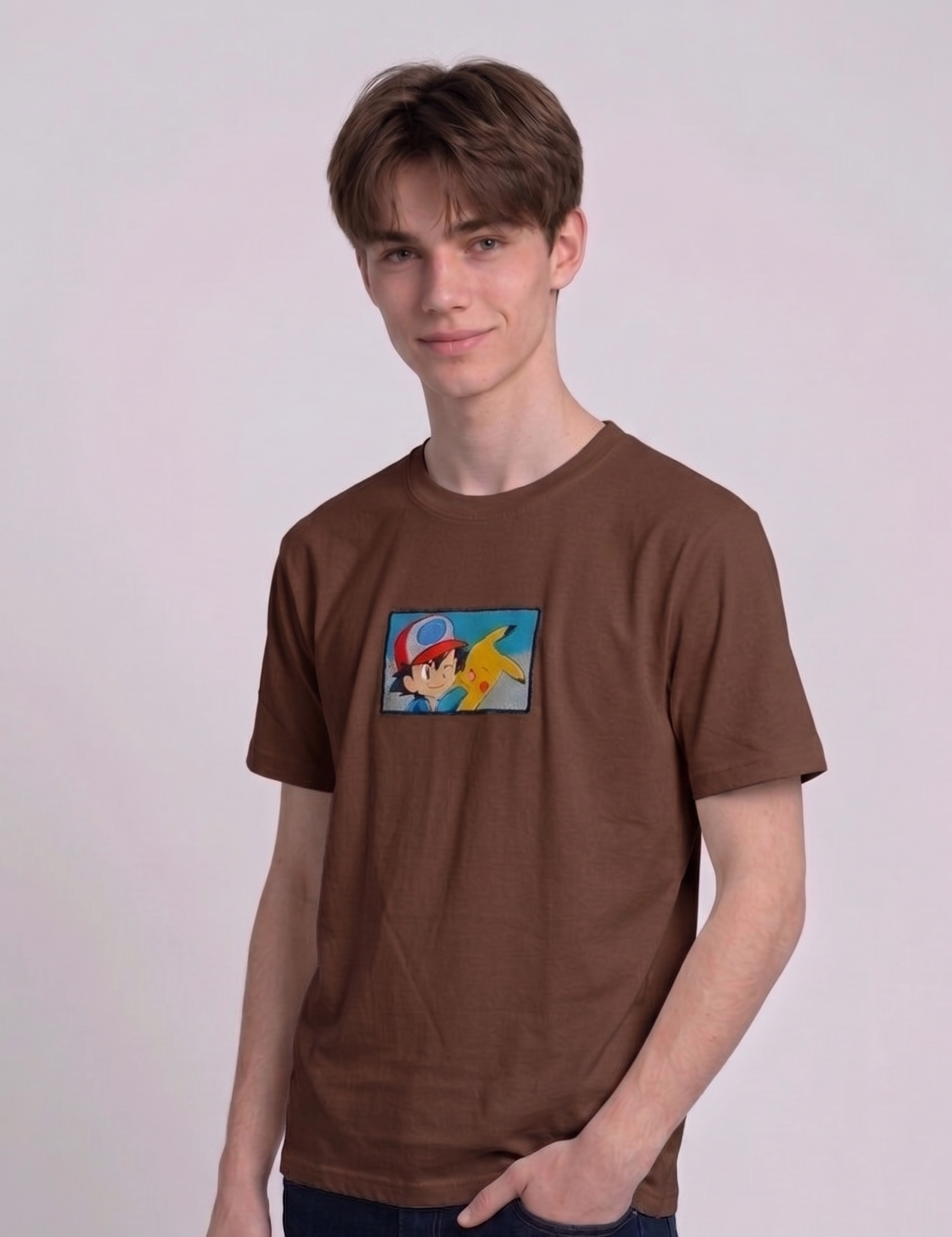 He is wearing , heavyweight cotton t-shirt with a detailed, colorful embroidered patch on the chest featuring anime characters Ash Ketchum (winking) and Pikachu.