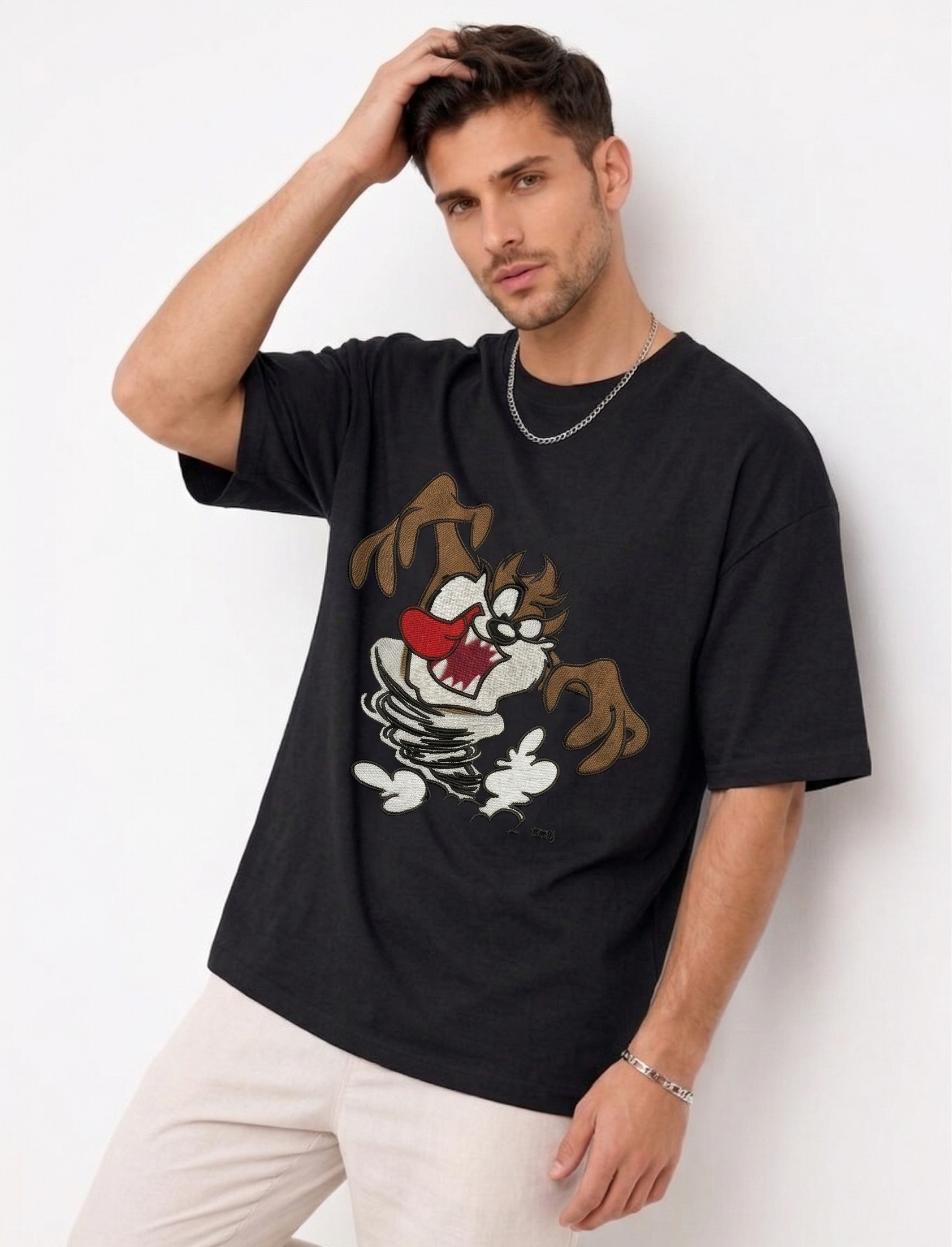 E-commerce product photo of a premium black streetwear t-shirt with custom character embroidery and a relaxed, oversized silhouette.
