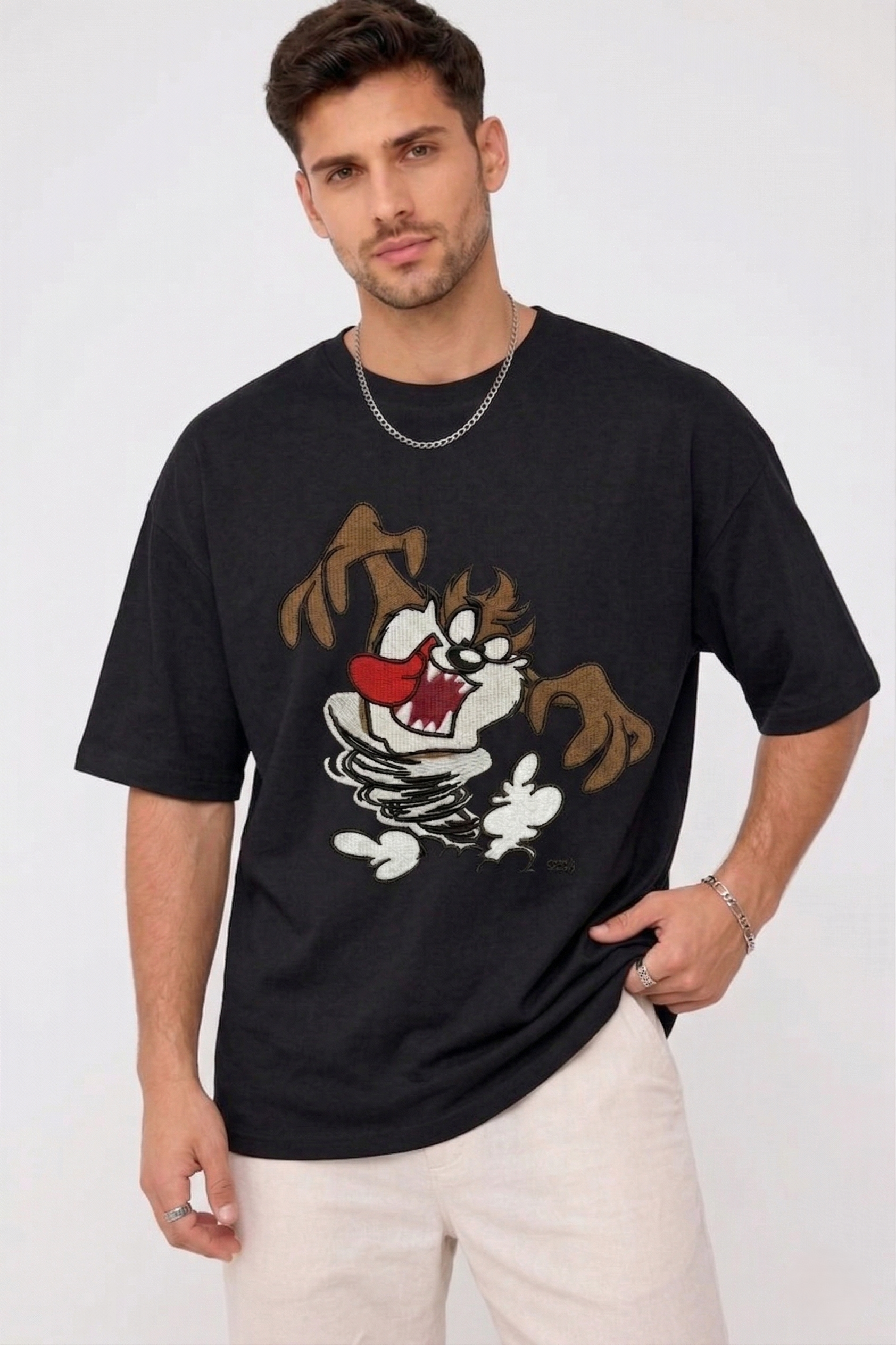 E-commerce product photo of a premium black streetwear t-shirt with custom character embroidery and a relaxed, oversized silhouette.