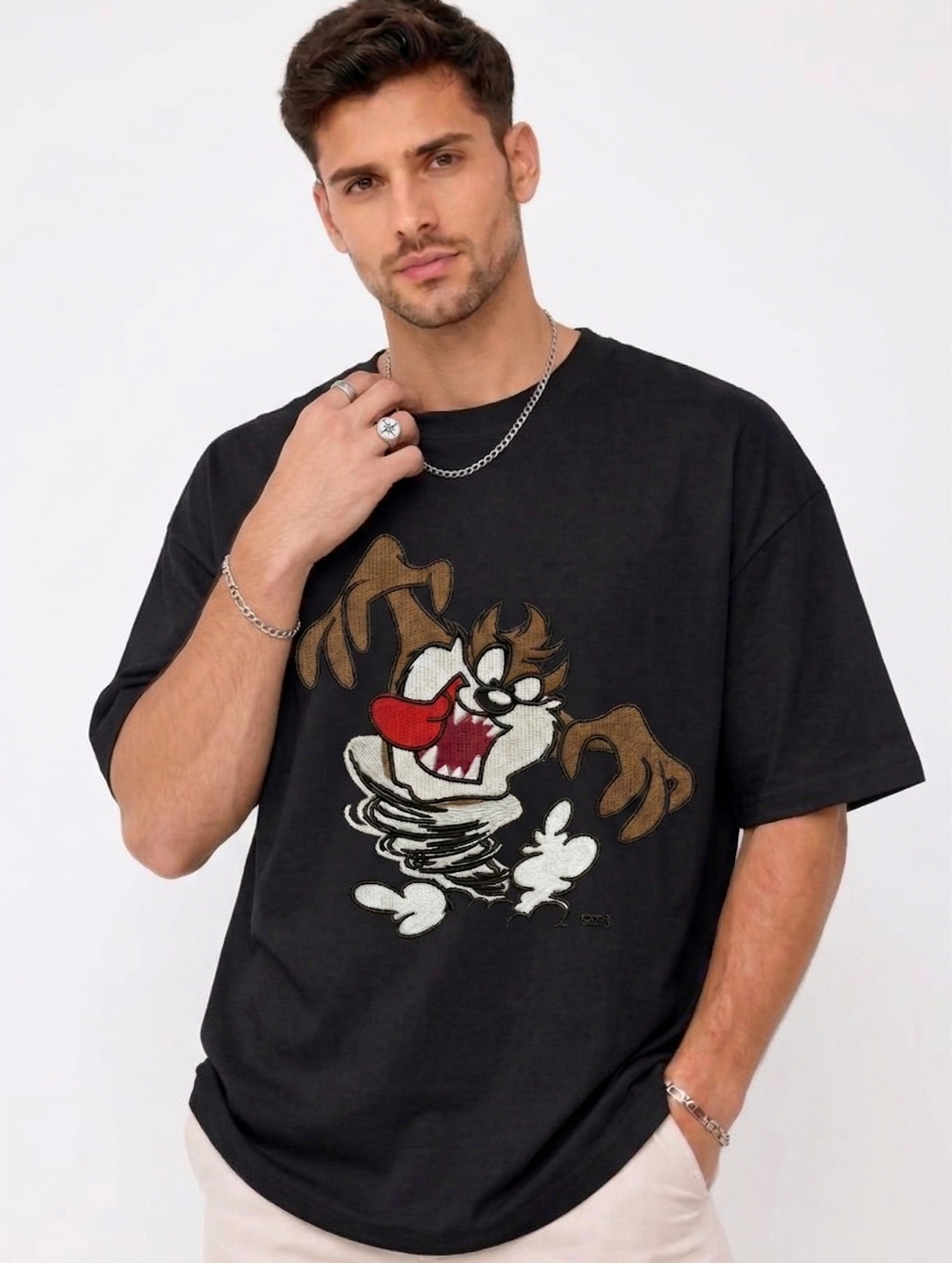 E-commerce product photo of a premium black streetwear t-shirt with custom character embroidery and a relaxed, oversized silhouette.
