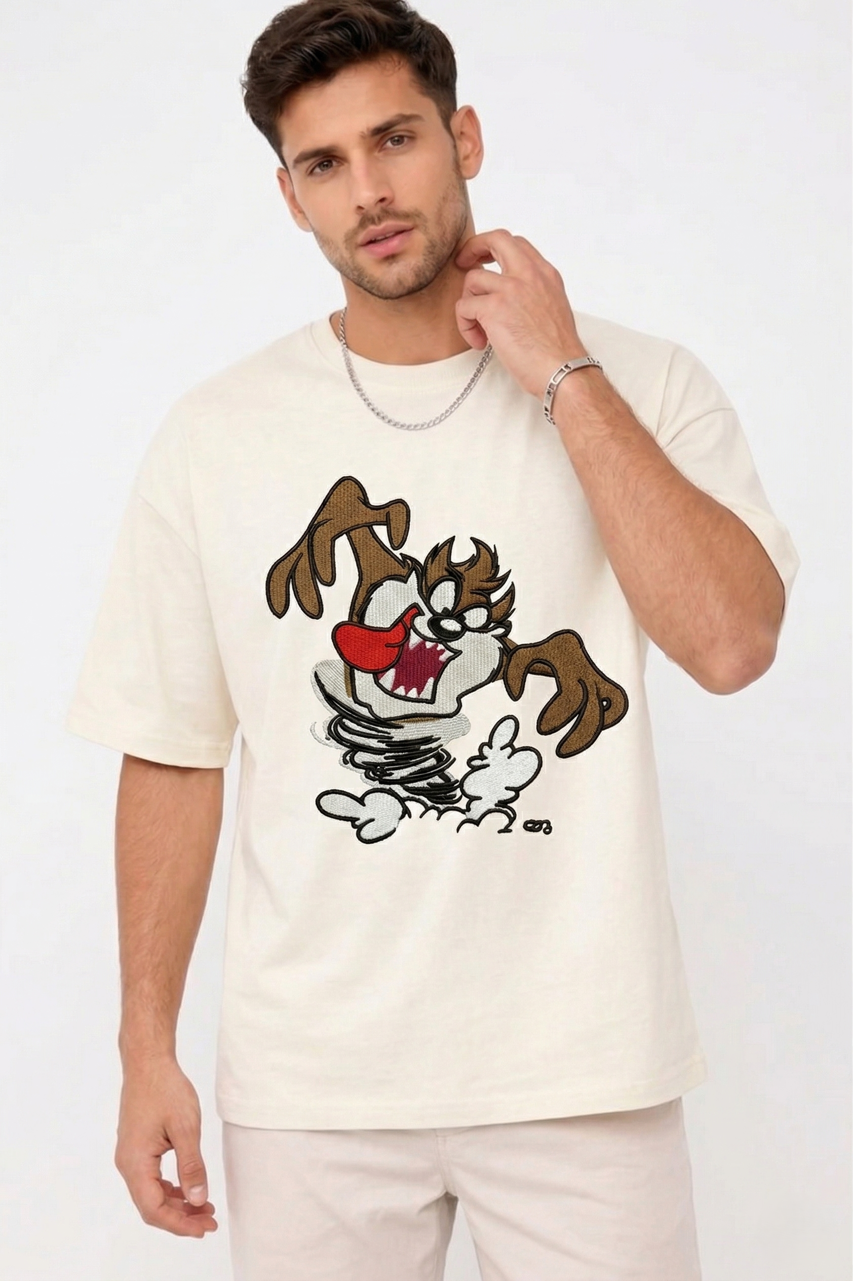 E-commerce product photo of a premium off-white streetwear t-shirt with custom character embroidery and a relaxed, drop-shoulder fit.