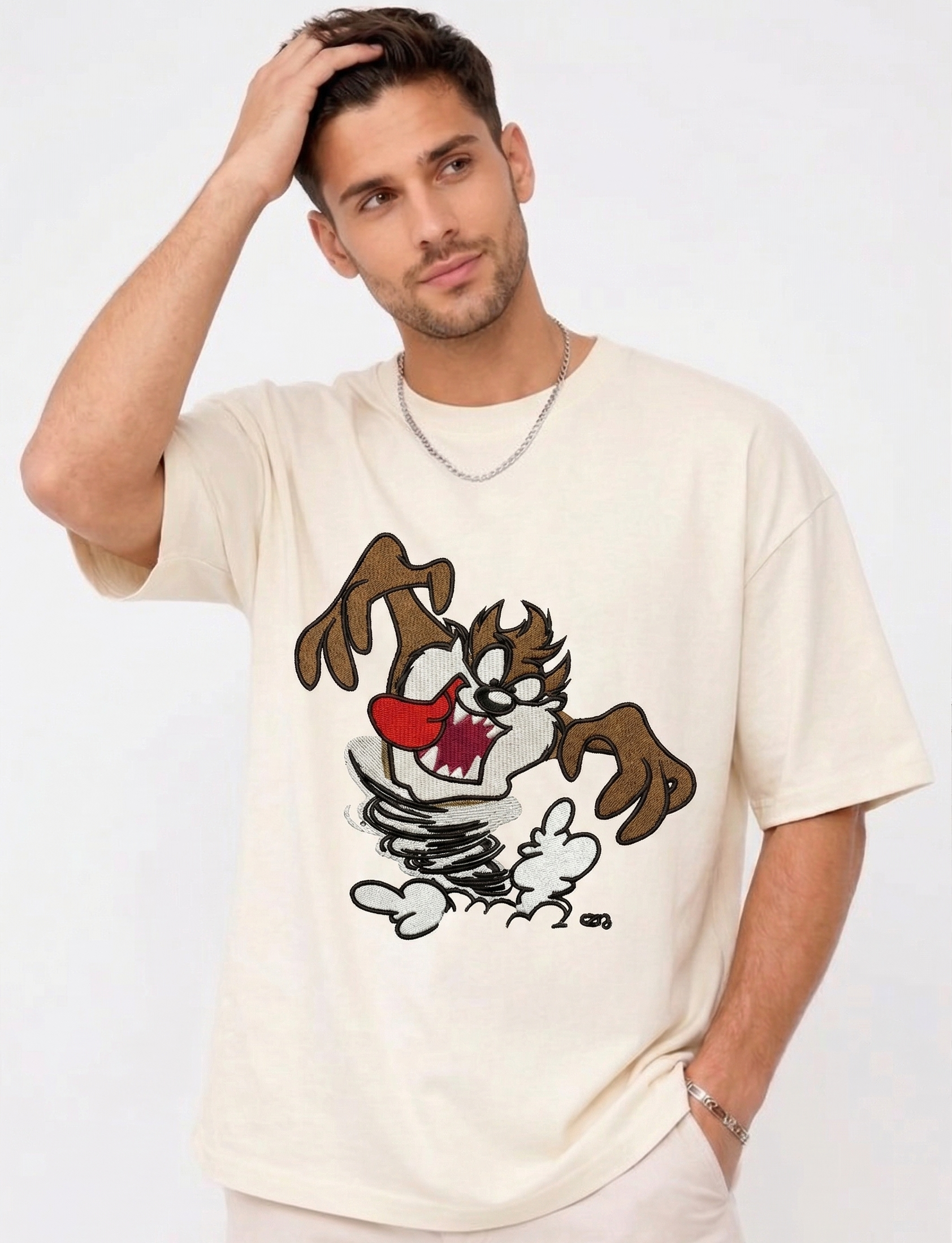 E-commerce product photo of a premium off-white streetwear t-shirt with custom character embroidery and a relaxed, drop-shoulder fit.