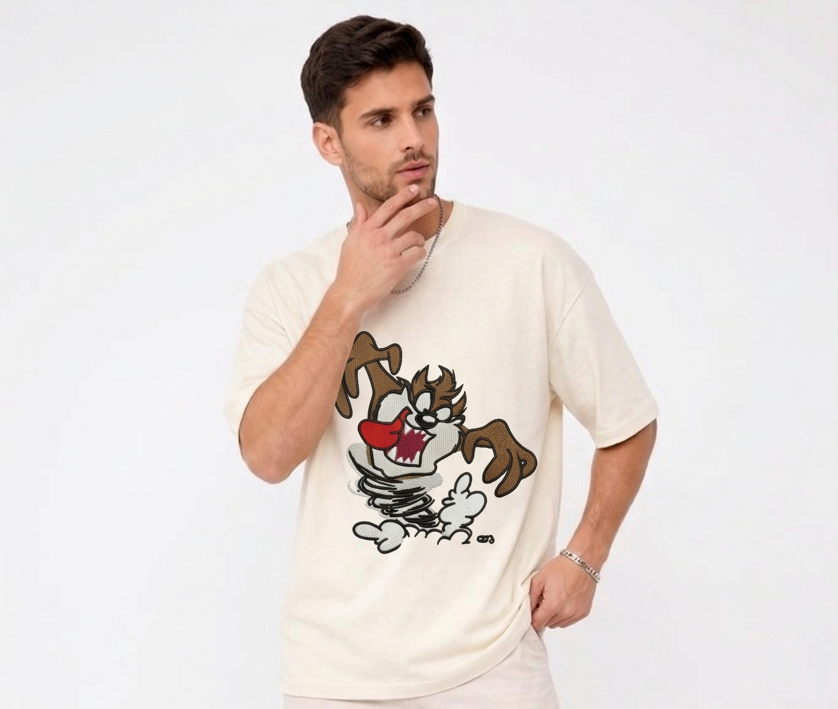 
E-commerce product photo of a premium off-white streetwear t-shirt with custom character embroidery and a relaxed, drop-shoulder fit.
