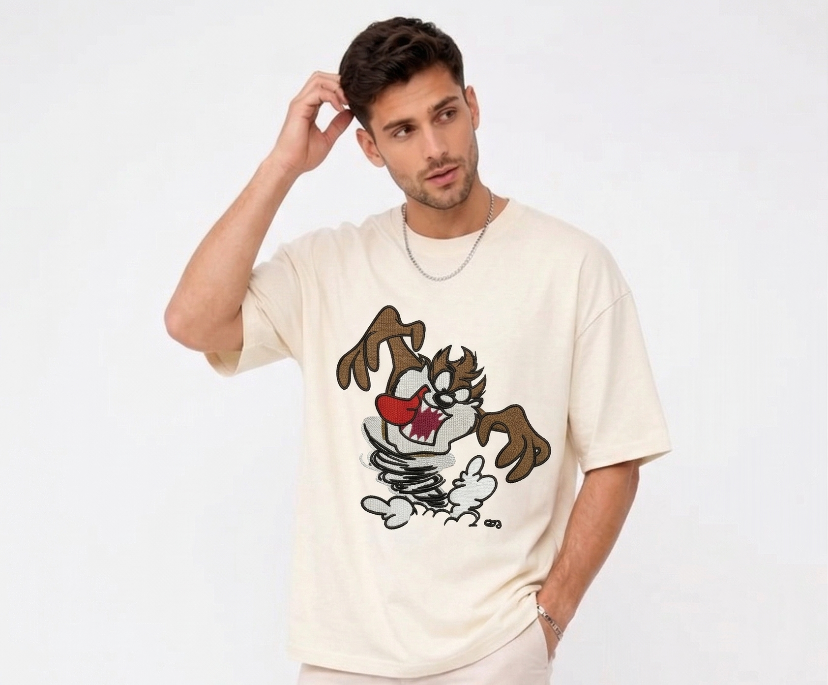 
E-commerce product photo of a premium off-white streetwear t-shirt with custom character embroidery and a relaxed, drop-shoulder fit.