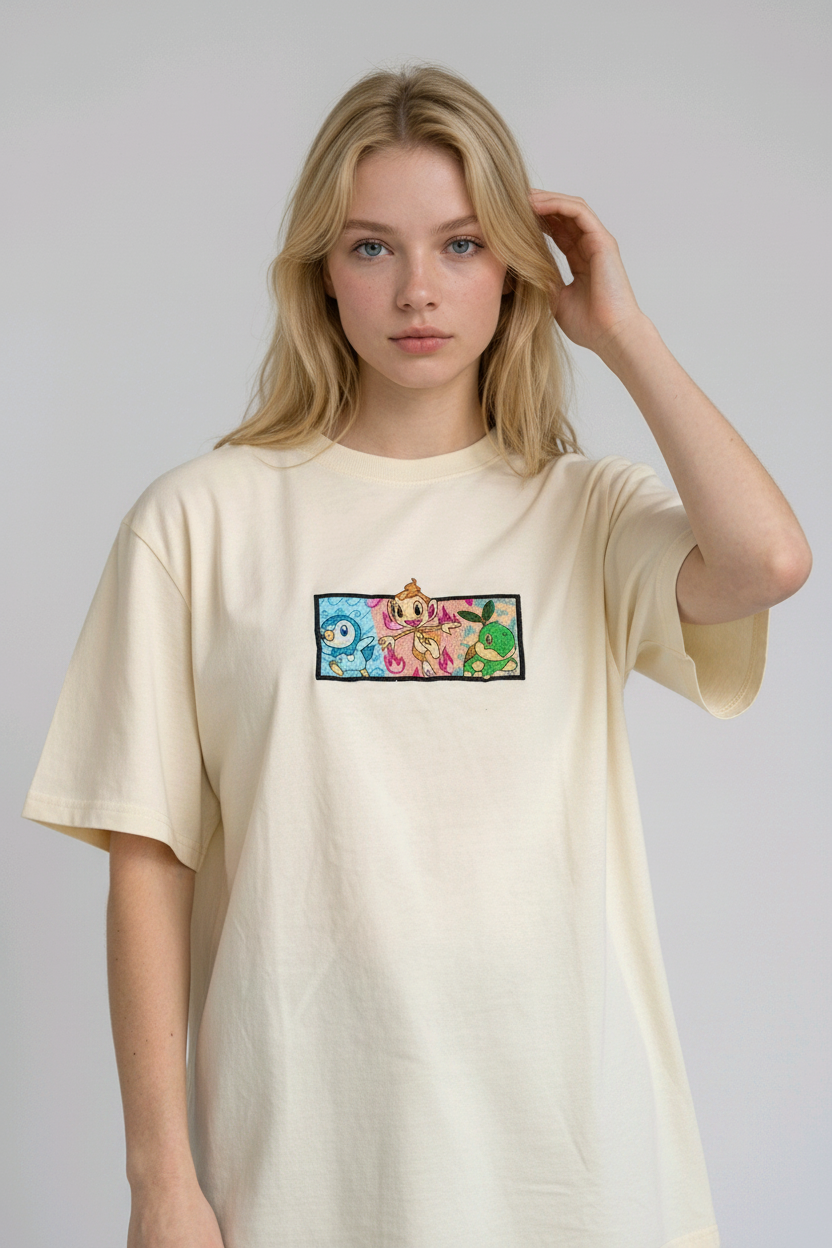 A young woman with wavy blonde hair standing against a plain grey studio background. She has her arms crossed and is wearing a white crew-neck t-shirt.

