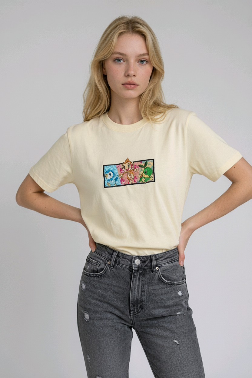 A young woman with wavy blonde hair standing against a plain grey studio background. She has her arms crossed and is wearing a white crew-neck t-shirt.

