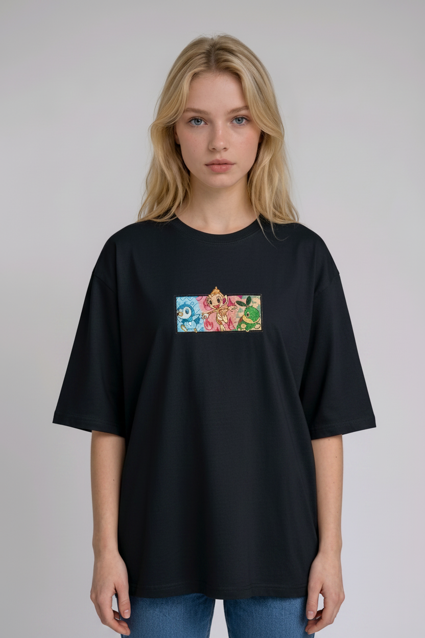 A young woman with wavy blonde hair standing against a plain grey studio background. She has her arms crossed and is wearing a black crew-neck t-shirt.
