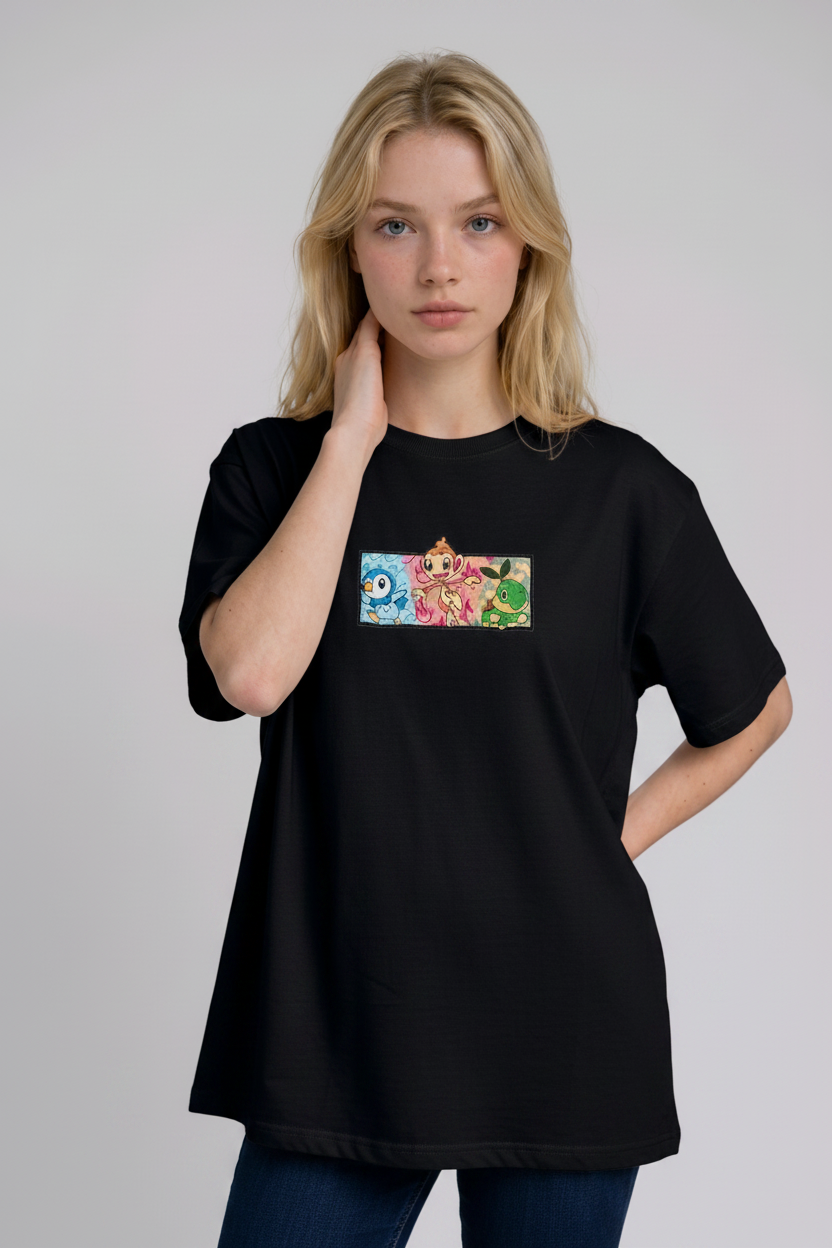 A young woman with wavy blonde hair standing against a plain grey studio background. She has her arms crossed and is wearing a black crew-neck t-shirt.
