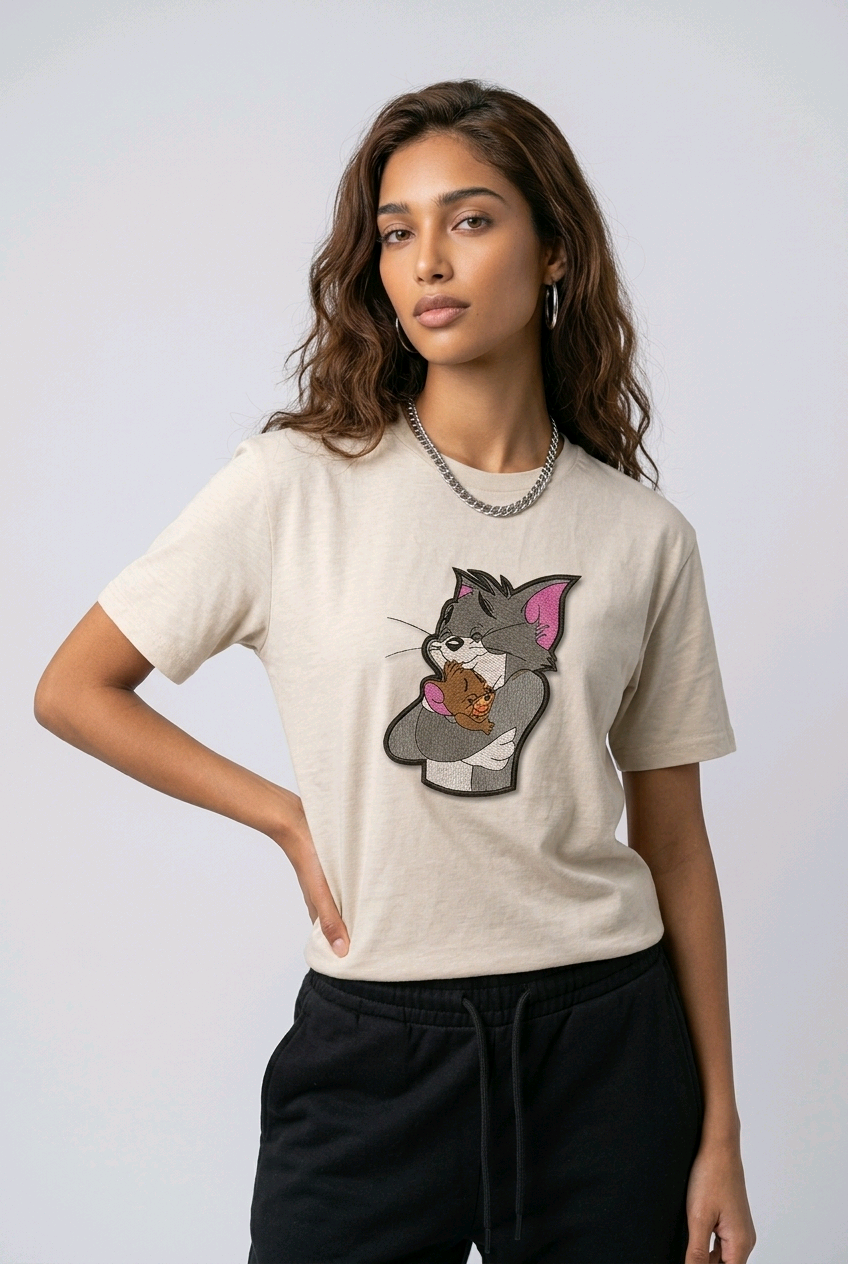 Woman wearing a beige t-shirt with a vintage Tom and Jerry cartoon patch.

